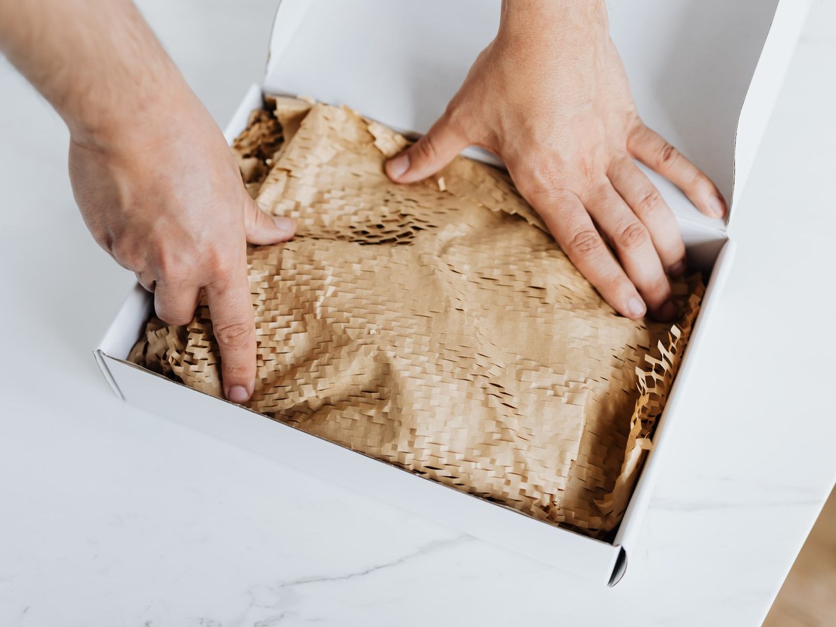 Hands packing an order into a white box on a clean worktop